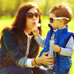 Mom and toddler boy blowing dandelion flowers