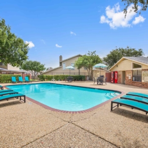 Alternative view of Pool with bright teal lounge furniture with large trees and beautiful blue sky in the background