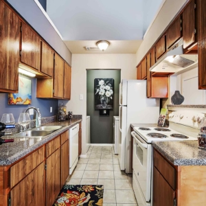 Galley kitchen of model home with white appliance package and re-finished counters