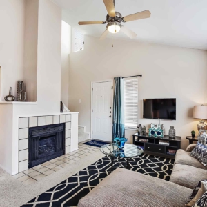 Alternative view of model home living room with wood burning fireplace, lofted ceilings and ceiling fan